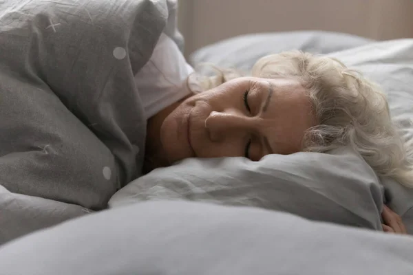 Wanita tua tidur di tempat tidur dengan selimut di kamar tidur yang nyaman — Stok Foto