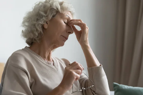 Old woman took off glasses to relief eyestrain feelings — Stock Photo, Image