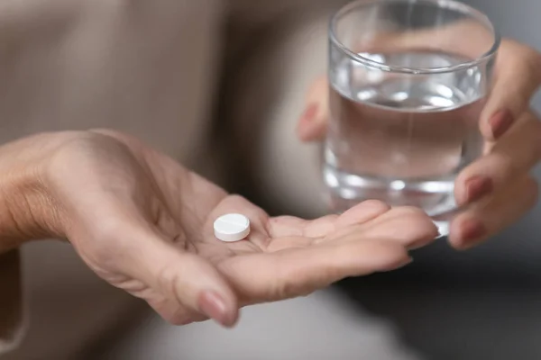 Senior woman hands holding pill and glass of water closeup — Stock Photo, Image