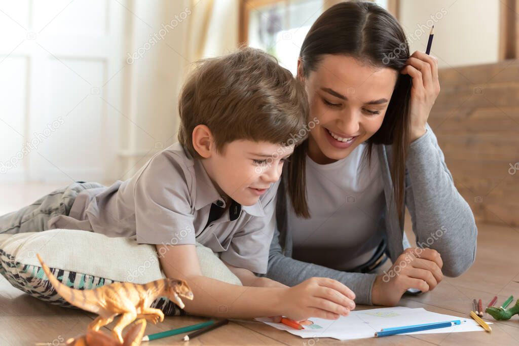 Happy little child boy hand drawing pictures with mom.