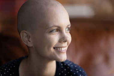 Gülümseyen genç hasta kadın iyileşme hayali ile uzaklara bak.