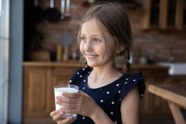 Gülümseyen küçük kız lezzetli süt bardağı içiyor.
