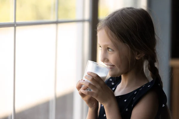 Ευτυχισμένο κοριτσάκι κοίτα στο παράθυρο πίνοντας γάλα — Φωτογραφία Αρχείου