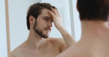 Genç ve yakışıklı Avrupalı bir adam saç durumunu değerlendiriyor..