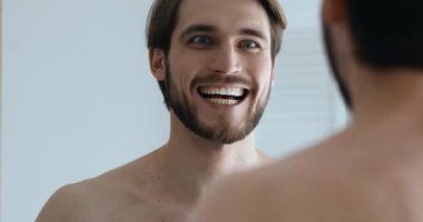 Genç beyaz adam aynaya bakıyor, sabahları kendini cesaretlendiriyor..