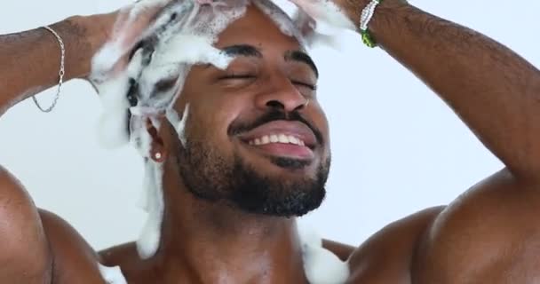 Glad avslappnad vacker afrikansk etnicitet man tvätta huvudet med schampo. — Stockvideo