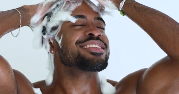 Gelukkig ontspannen knappe Afrikaanse etniciteit man wassen hoofd met shampoo. — Stockvideo