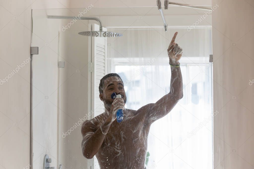 Positive African American man having fun in bathroom, singing