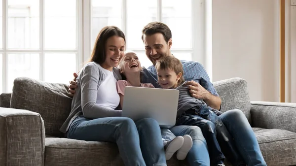 Happy bonding family enjoying watching funny comedian movie on laptop.