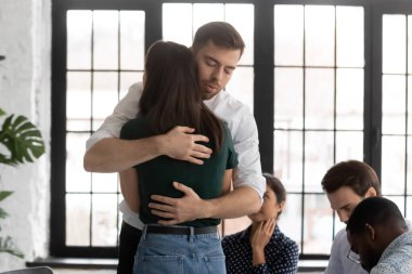 Üzgün adam ve kadın grup terapisinde sarılıyorlar.