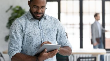 Bilgisayar tableti kullanarak odaklanmış Afrikalı Amerikalı işadamını kapat