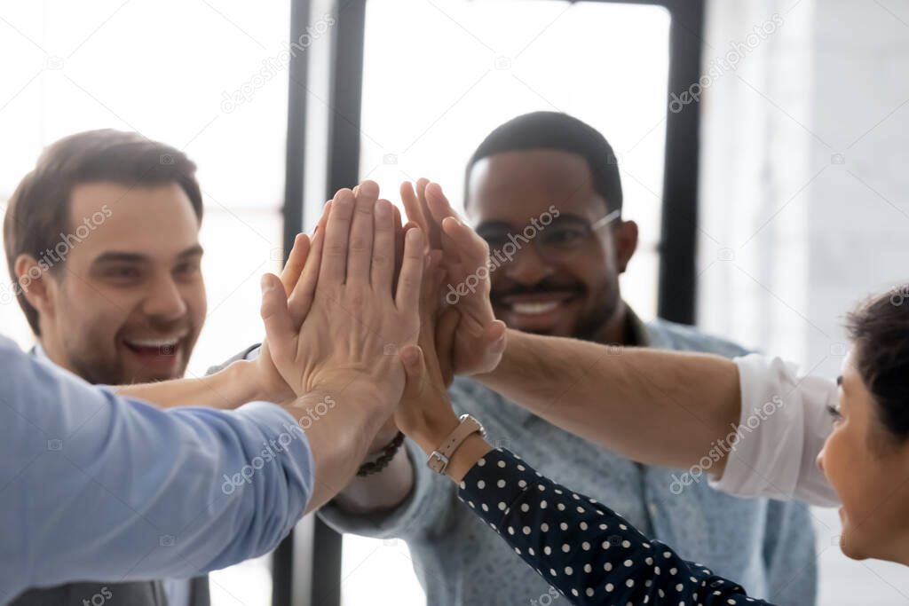 Close up diverse business people joining hands, giving high five