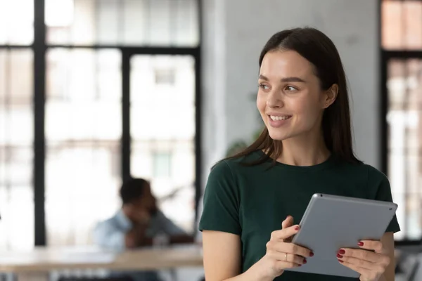 Close up smiling dreamy businesswoman intern holding computer tablet