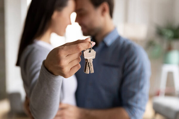 Emotional happy family couple demonstrating keys from new house.