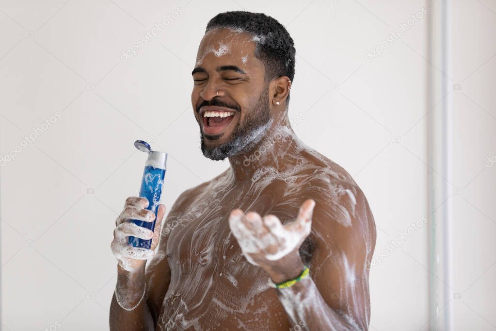 Smiling cheerful African American young man singing in shower