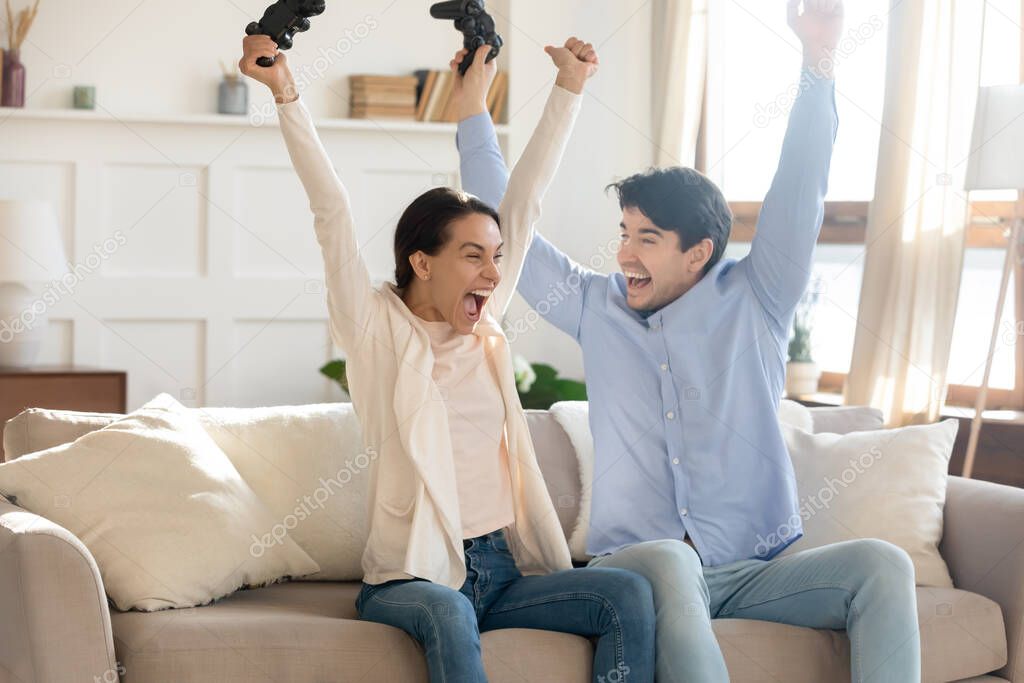 Euphoric positive young couple celebrating winning online video game competition.