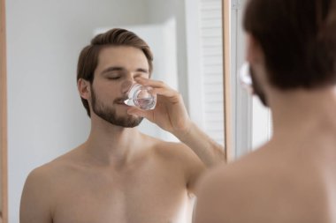 Aynanın yansıması yakışıklı adam saf maden suyu içiyor.