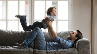 Mutlu genç baba oğluyla uçak oyunu oynuyor..