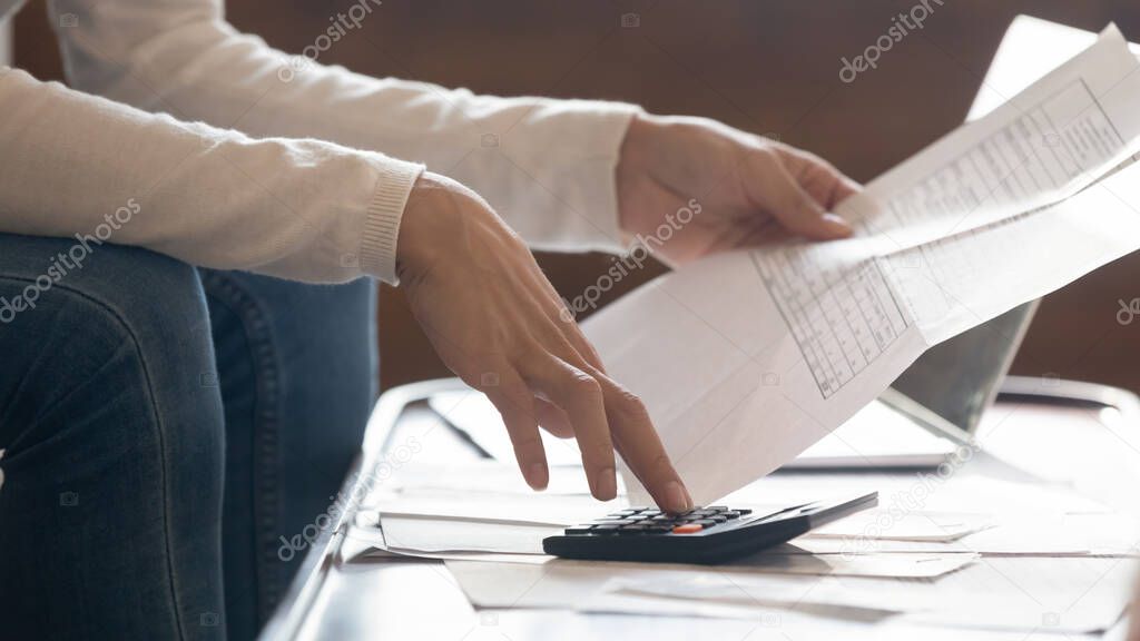 Focused young woman managing household finances indoors.