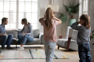 Mutsuz küçük çocuklar tartışan ebeveynlere bakıyor..