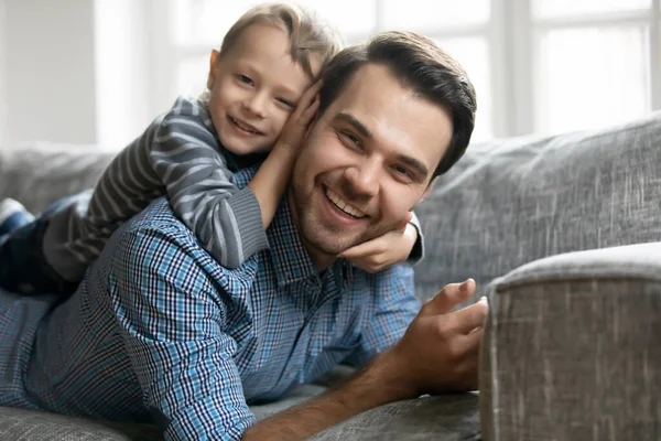 Portrait of adorable little son lying on fathers back. — Stock Photo, Image