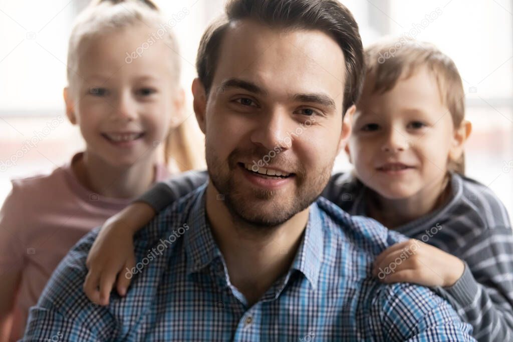 Young handsome man with children behind holding video call.