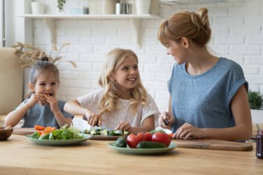 İki küçük kız kardeş anneme sebze salatası hazırlamada yardım ediyor.