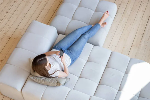 Top view of young lady using smartphone at home — Stock Photo, Image