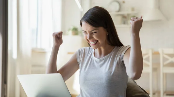 Mujer joven emocionada mirando en la pantalla de su computadora portátil —  Fotos de Stock
