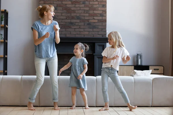 Active happy mother and daughters dancing and jumping at home — Stock Photo, Image