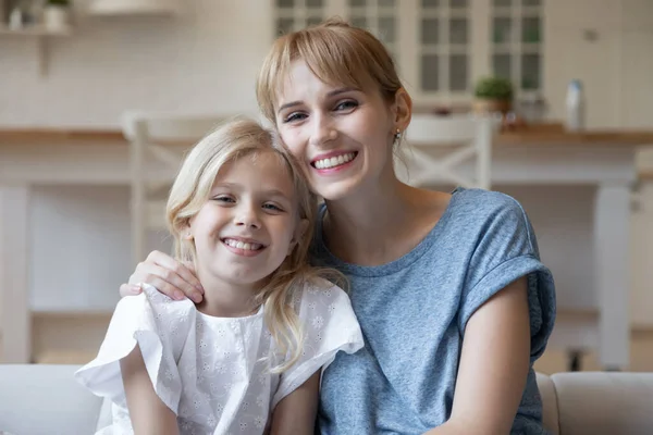 Портрет усміхненої матері і маленької дочки, що обіймається вдома — стокове фото