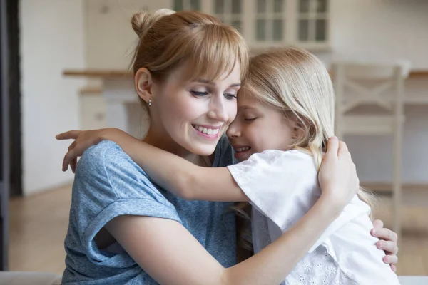 Leende liten flicka omfamnar lycklig mor eller barnflicka — Stockfoto