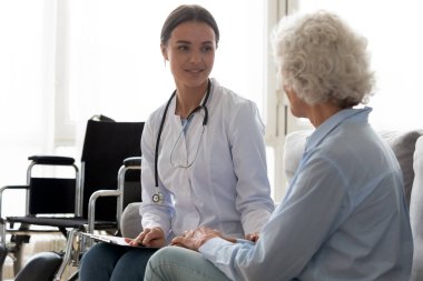 Genç bayan doktor engelli yaşlı hastayı ziyaret ediyor..