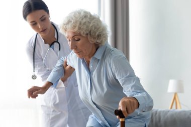 Dikkat et genç bayan fizyoterapist yaşlı engelli hastaya yardım ediyor..