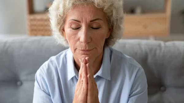 Mujer mayor consciente rezando a Dios con los ojos cerrados. — Foto de Stock