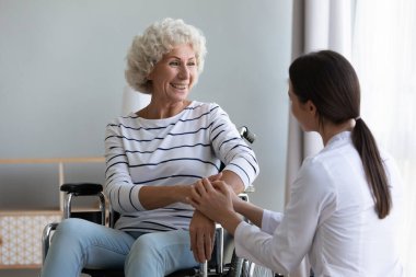 Genç tıp çalışanı yaşlı mutlu hastaya psikolojik yardım yapıyor..