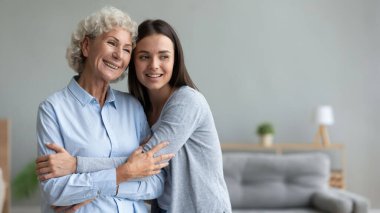 Mutlu, güzel, yetişkin bir kız, orta yaşlı bir anneye sarılıyor..