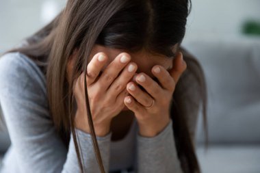 Mutsuz genç kadın, ellerinde yüzünü gizliyor, çaresiz hissediyor..