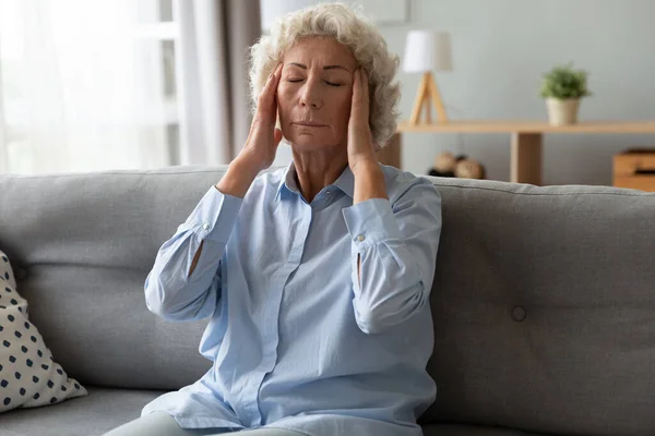 Unhealthy worried old mature woman massaging temples. — Stock Photo, Image