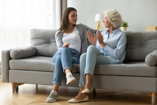 Joven feliz hermosa mujer hablando con ancianos mamá en el interior. —  Fotos de Stock