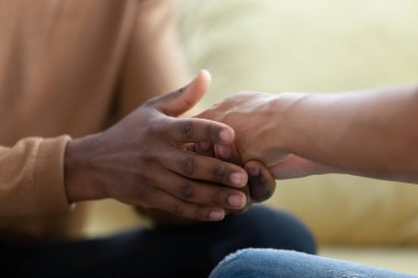 Afrikalı koca, çift ırklı eşin elini tutuyor özen ve sevgiyle.