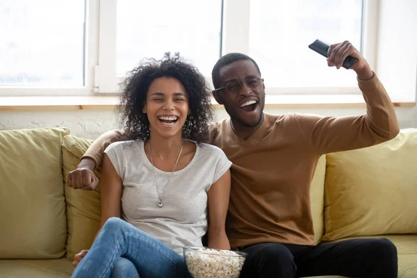 Feliz emocionado negro pareja disfrutando viendo deporte partido en casa —  Fotos de Stock