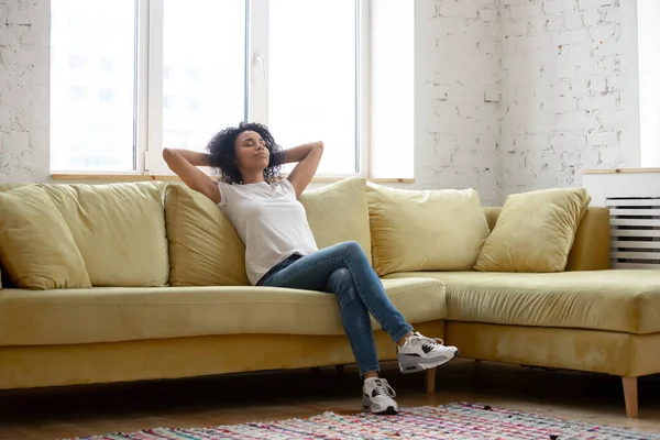 Szczęśliwy spokojny biracial dziewczyna medytując na kanapie w salonie — Zdjęcie stockowe