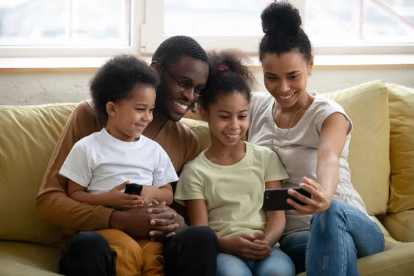 Heureuse famille africaine de quatre personnes faisant un vidéocall dans le salon — Photo