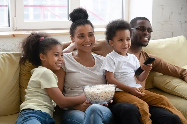 Heureux couple africain avec des enfants se détendre à la maison regarder la télévision — Photo