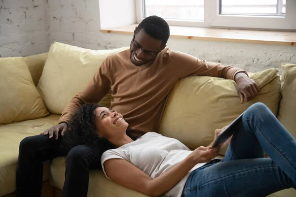 Positiv lächelndes afrikanisches verliebtes Paar, das zusammen auf dem Sofa ruht — Stockfoto