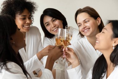 Beş çok ırklı kadın şampanya içip köpüklü şarap içiyor.