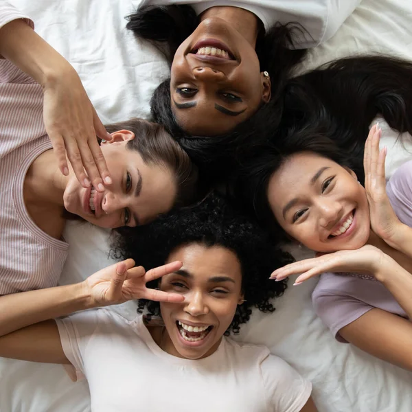 Acima vista multiétnica meninas rostos deitado se divertindo dentro de casa — Fotografia de Stock