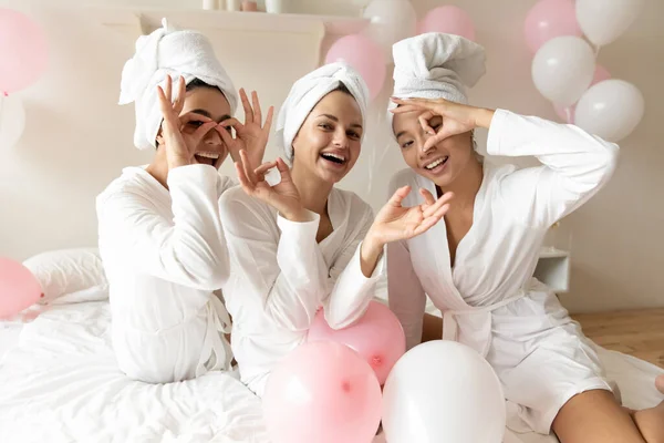 Women in bathrobes making binoculars with fingers celebrating bachelorette party — Stock Photo, Image