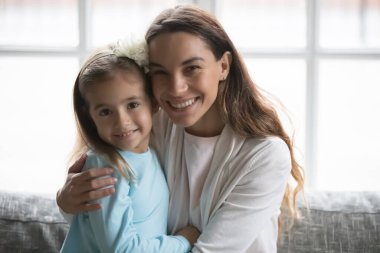 Mutlu, genç, melez anne, küçük tatlı kızı kucaklıyor..